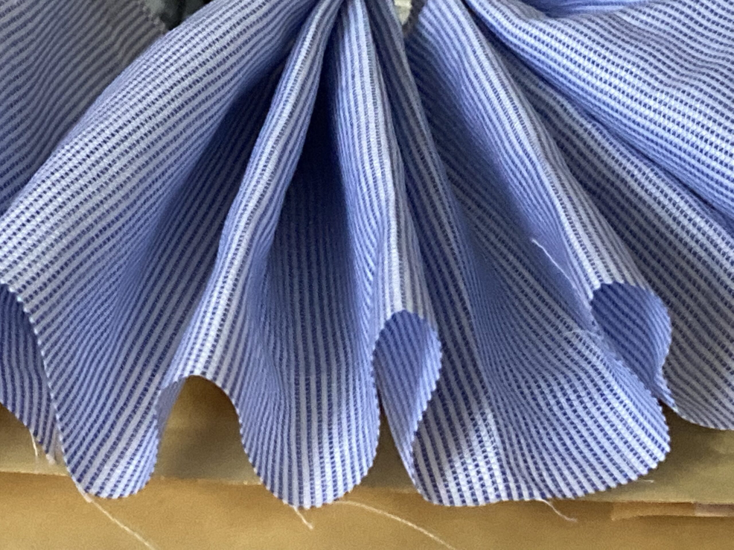 Image show a gathered piece of shirt material from remenants of a shirt factory in Derry. The material is thinly striped and is light blue and white in colour.